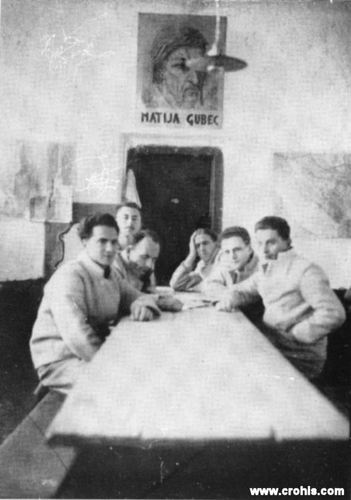 Članovi HSS-a na robiji u Lepoglavi. Uz zatvor u Srijemskoj Mitrovici i zatvor u Lepoglavi, u kojem je snimljena ova fotografija, bila je robijašnica namijenjena političkim zatvorenicima. Boravak u zatvoru korišten je i za obrazovanje kako svjedoče zemljopisne karte u pozadini. Kasnija komunistička vlast tako je zatvore kraljevine Jugoslavije nazivala „crvenim univerzitetima“. Veliki portret Matije Gupca izraz je ideologije HSS koja je u vođi seljačkog ustanka iz 16. st. vidjela svoga prethodnika. 